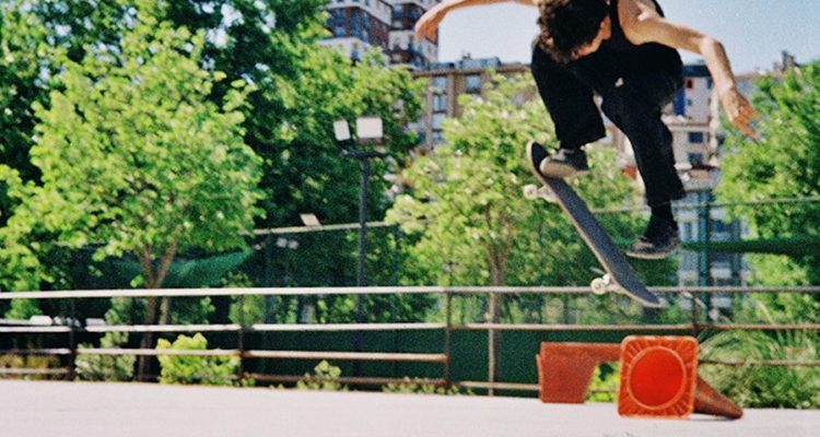 A skateboarder performs an aerial trick in an outdoor park.